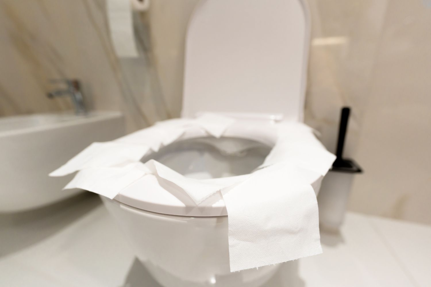 Vécépapírral körberakott vécéülőke fehér mellékhelyiségben