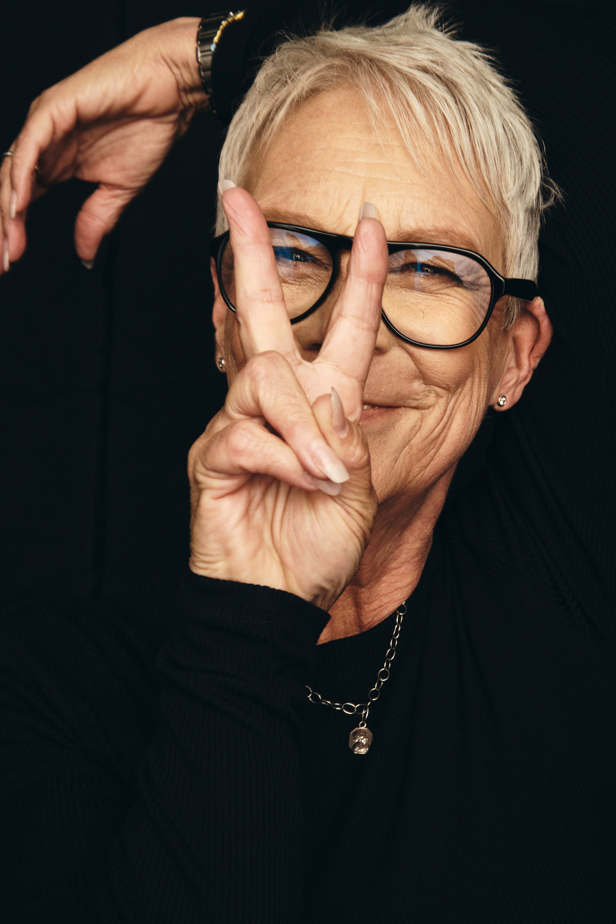 Jamie Lee Curtis fekete felsőben, arca előtt az ujjait felemelve