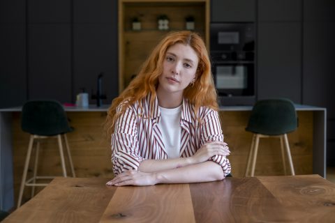 Fiatal nő komoly arccal néz a kamerába