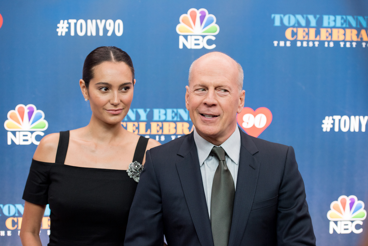 Emma Heming és Bruce Willis kék NBC feliratú háttér előtt