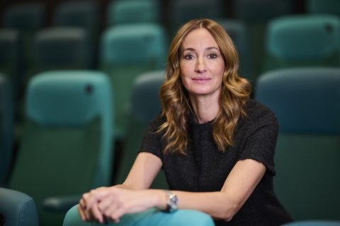 Epres Panni zöld széksorok között ül fekete pólóban és a kamerába néz