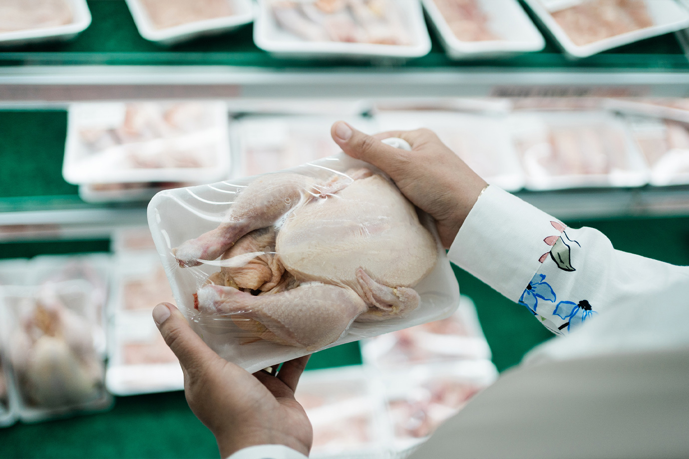 Egy nő egy egész csirkét tart a kezei között a boltban