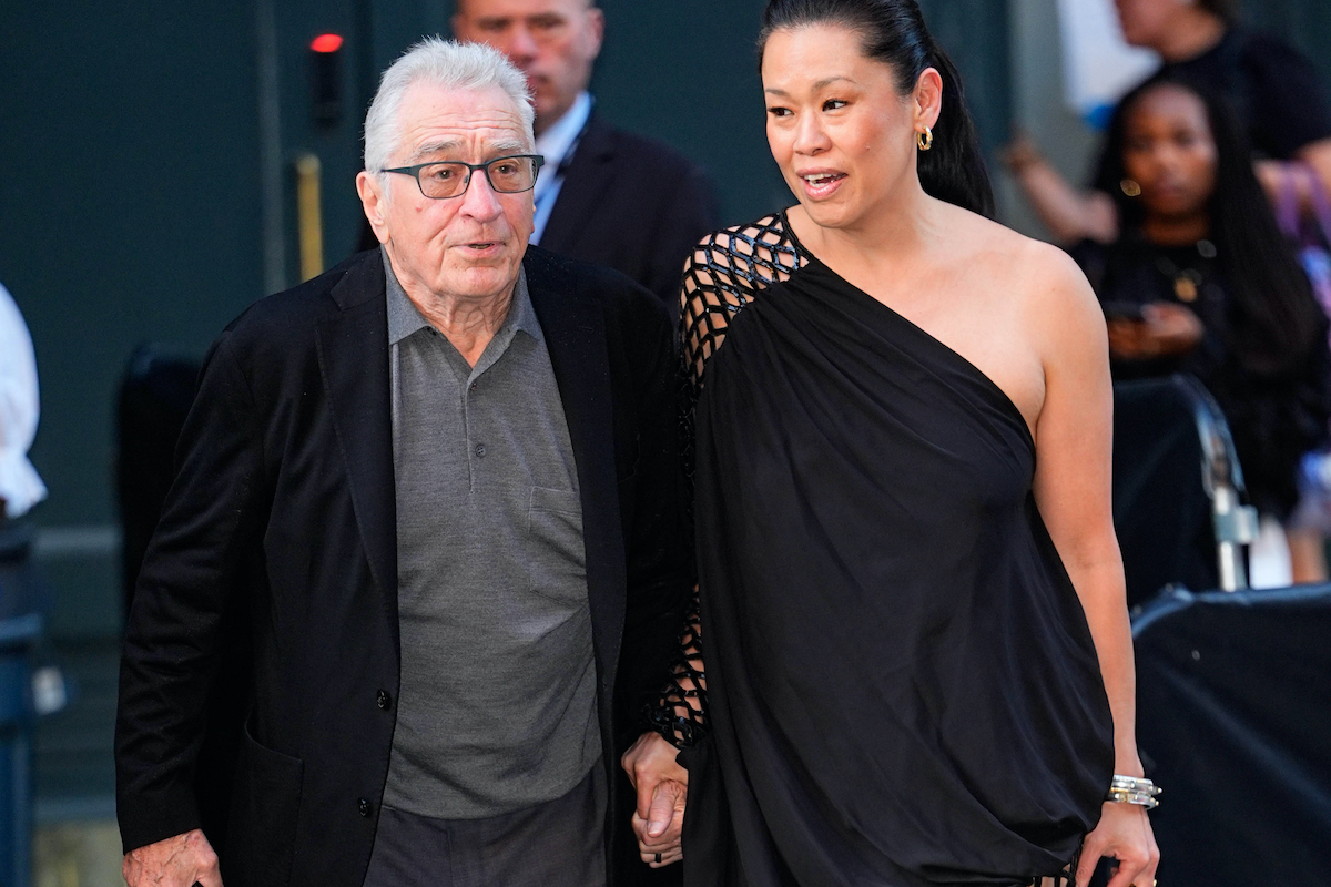 Robert De Niro zakóban és szürke ingben, és Tiffany Chen fekete félvállas ruhában, kézen fogva, emberek között