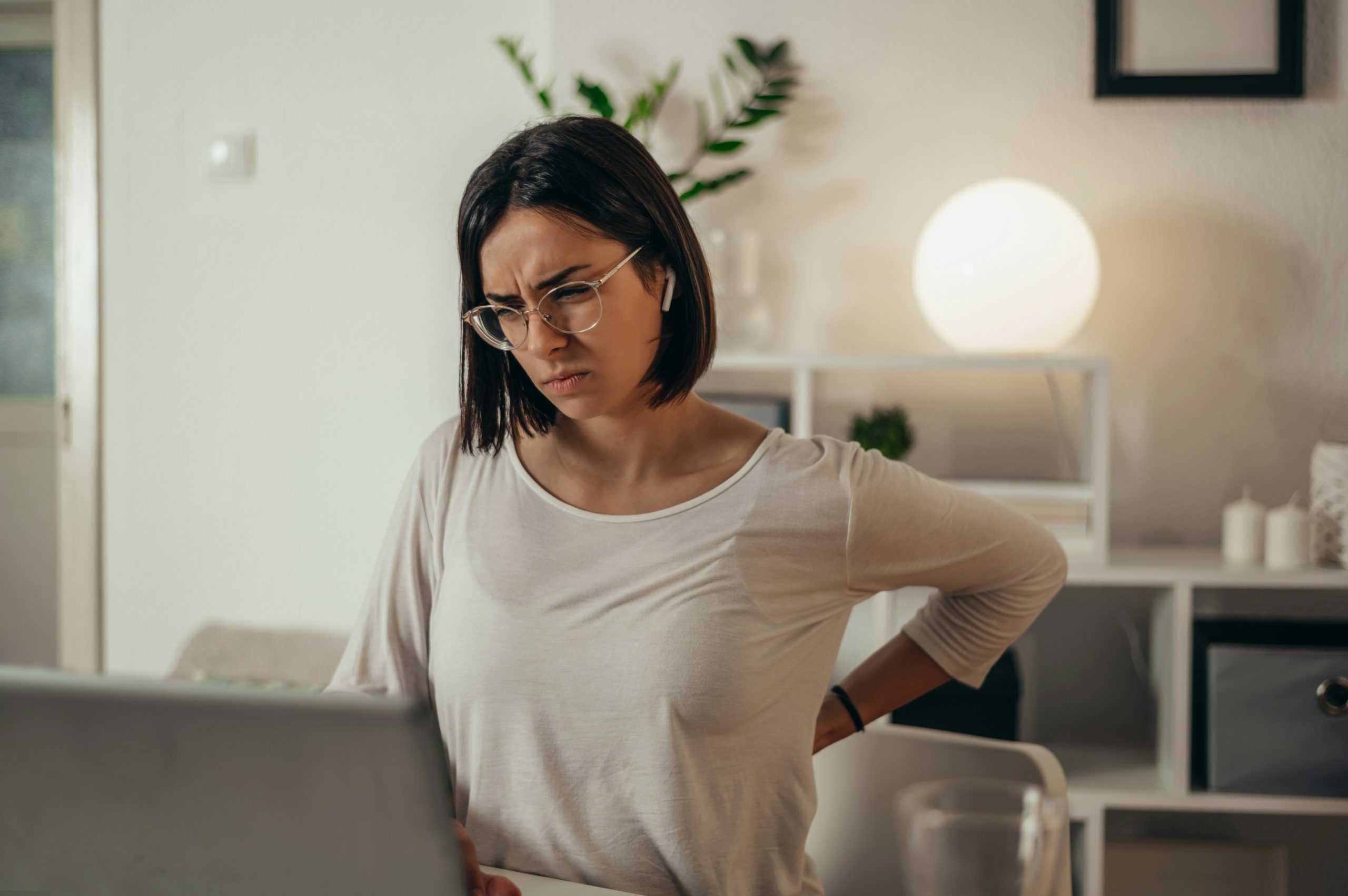 hoseg-nyar-kronikus-gyulladas-betegseg | Marie Claire Szemüveges nő laptop előtt ülve a derekát fájlalja