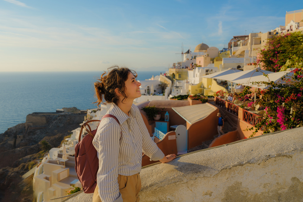Egy nő élvezi a napsütést Oia falura Santorini szigetén alkonyatkor görögországi utazása során