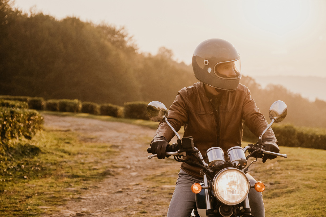 Fiatal férfi ül motoron naplementekor