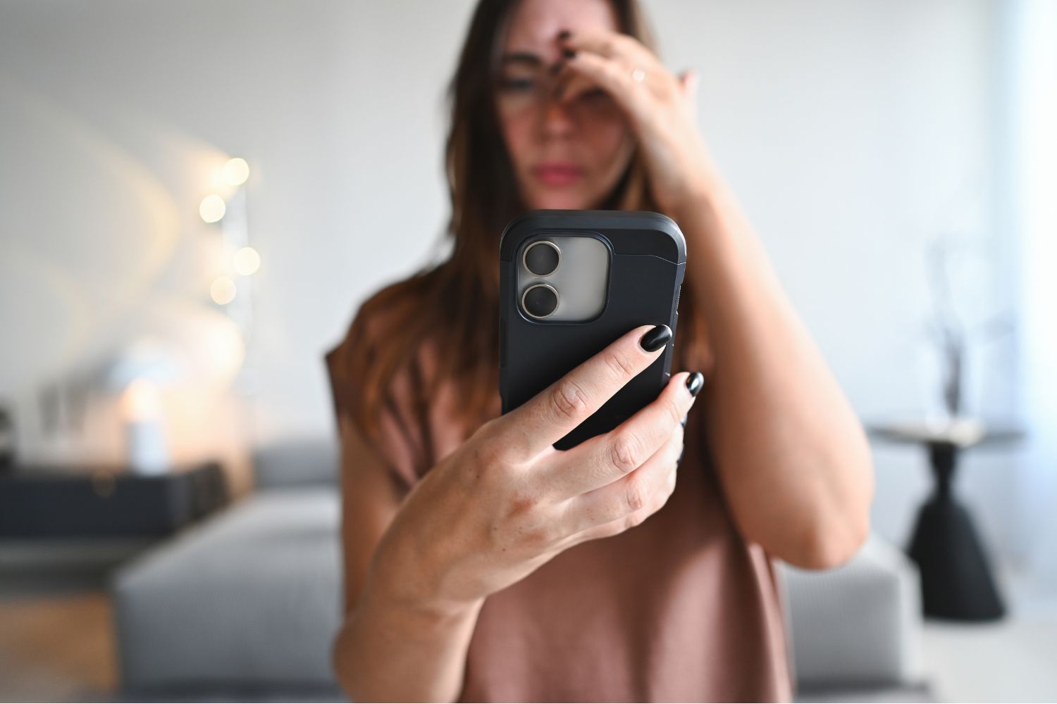 Nő aggódva nézi a mobiltelefonját