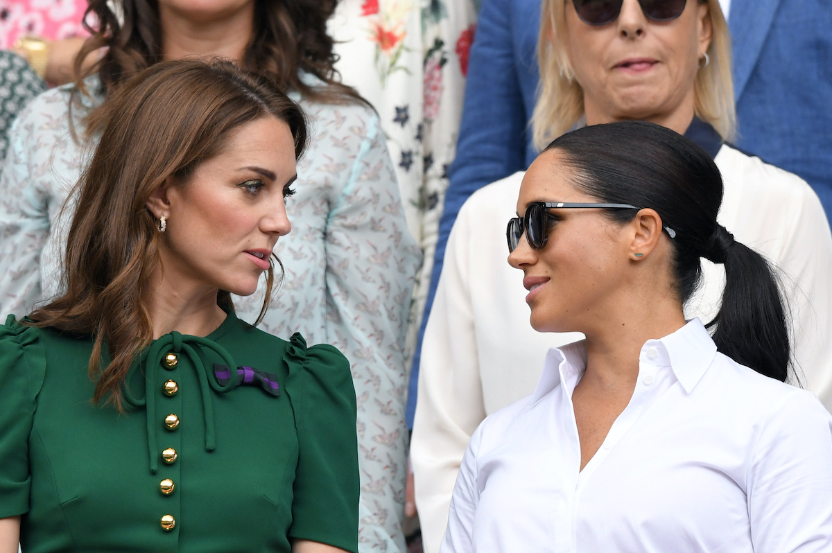 Katalin hercegné zöld felsőben és Meghan Markle napszemüvegben, fehér blúzban