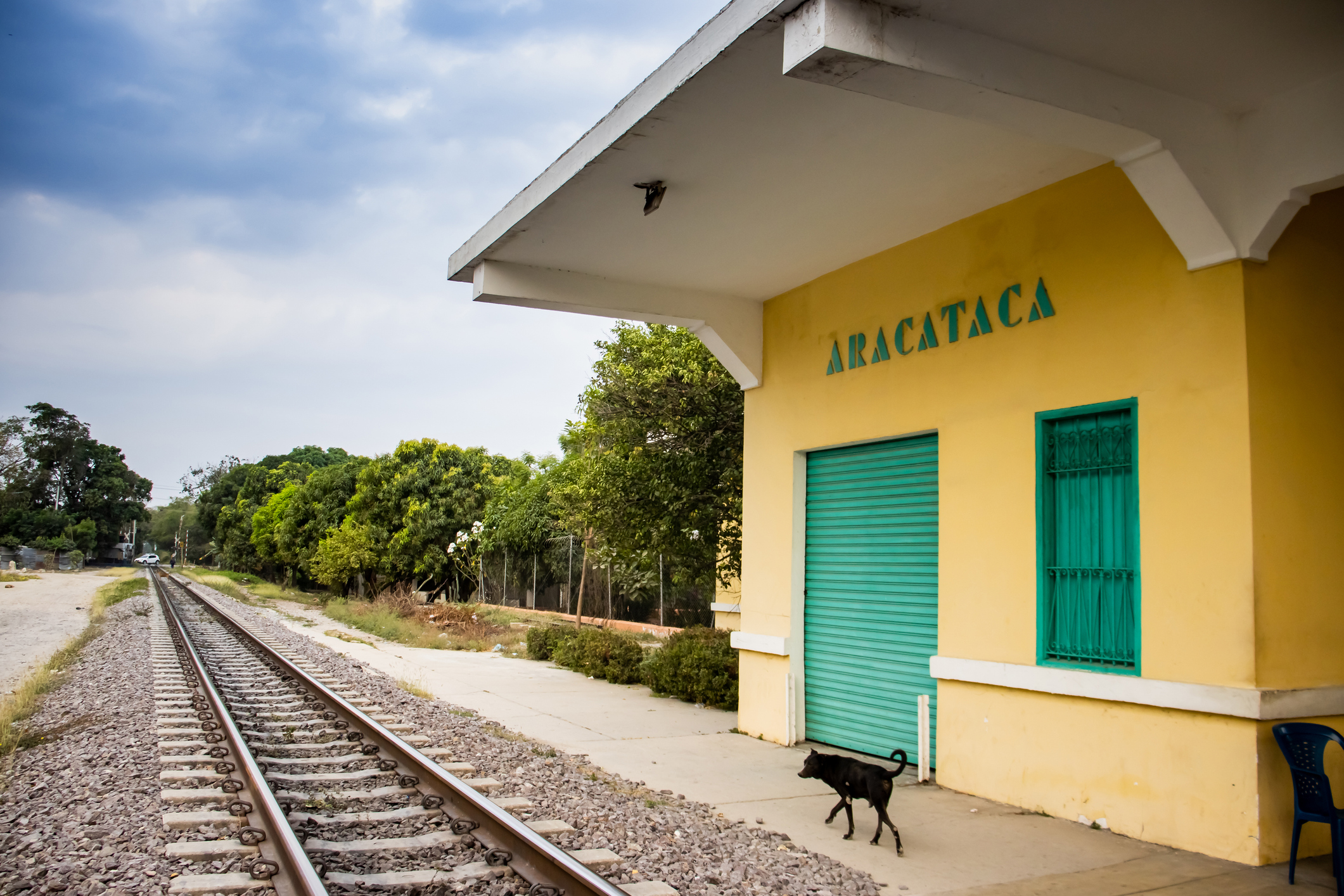 szaz-ev-magany-helyszin-macondo-aracataca | Marie Claire Aracataca feliratú állomásépület, sárga ház sínek mellett, zöld ajtóval és ablakokkal