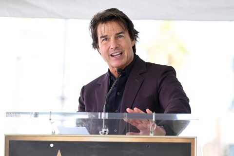 Tom Cruise lila zakóban pódiumon beszél