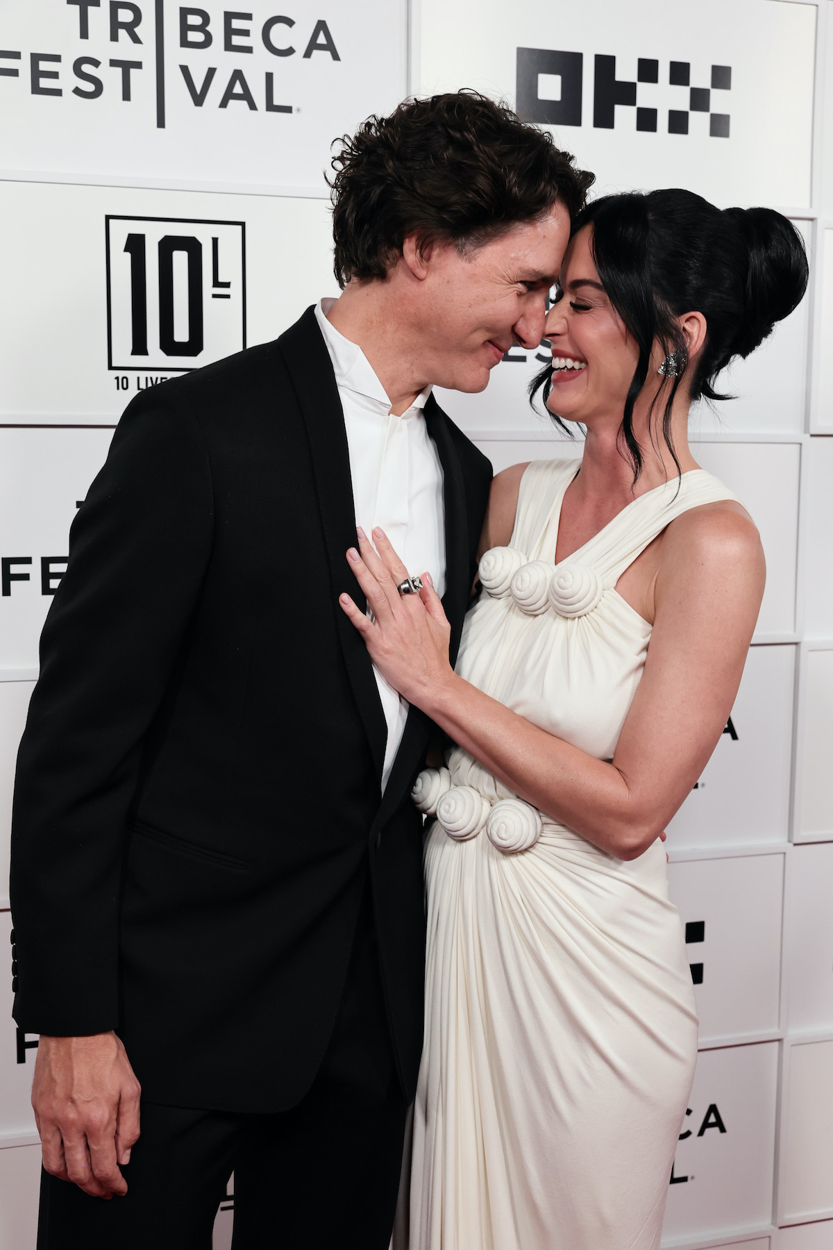 A fehér ruhás Katy Perry és Justin Trudeau egymás felé hajolnak