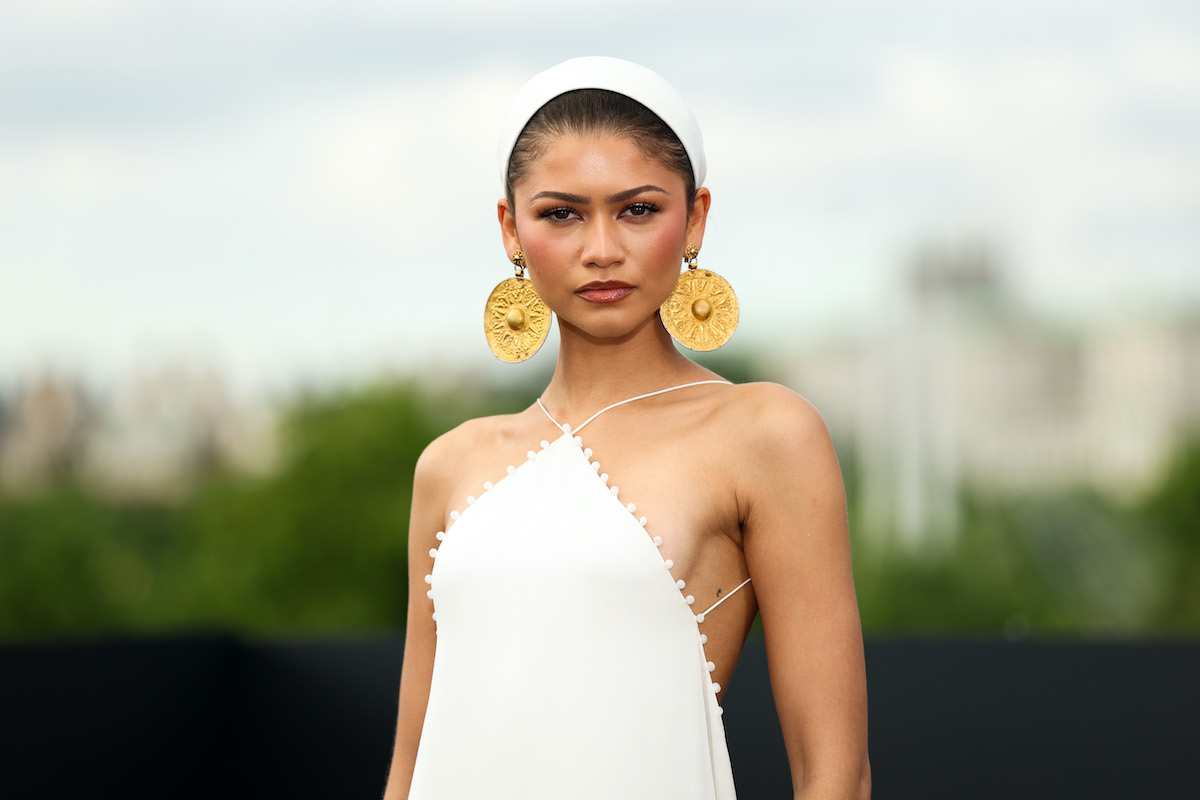 Zendaya nagy fülbevalókkal, fejkendővel és fehér ruhában