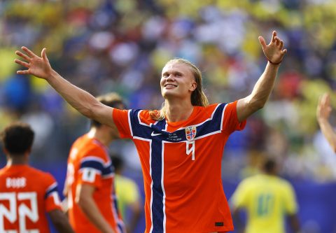 Erling Haaland piros mezben feltett kézzel és mosolyogva fut a pályán