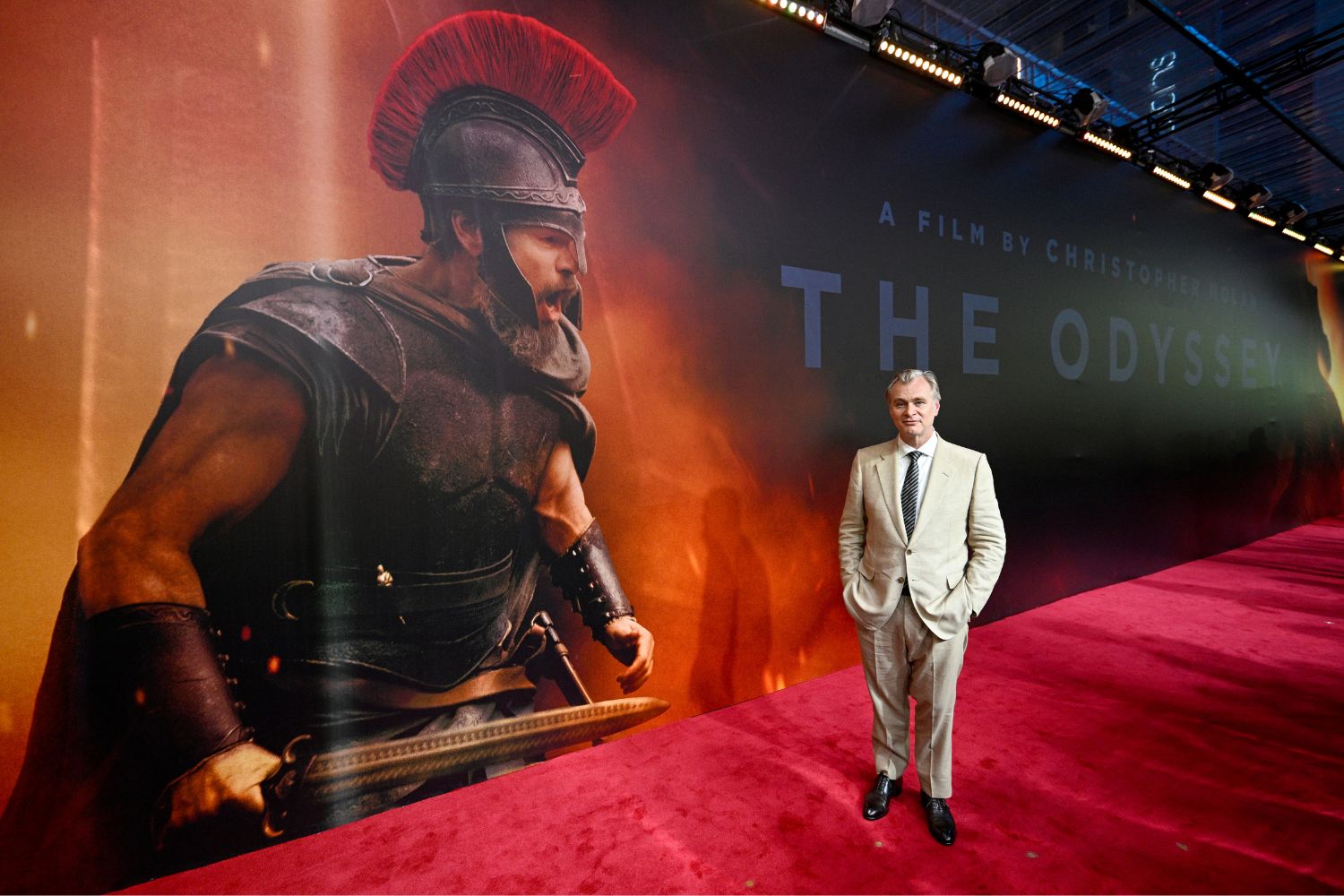 Christopher Nolan az Odüsszeia Mumbai premierjén a vörös szőnyegen hatalmas Odüszseia plakát mellett