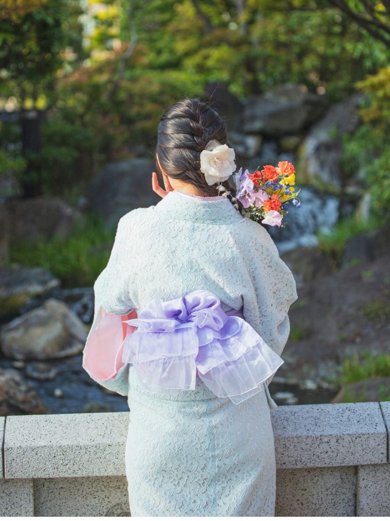 japan-kultura-nevadas | Marie Claire Japán visletbe öltözött lány virággal a kezében hídon áll háttal a kamerának