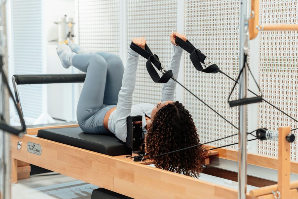 reformer-pilates-leengedett-haj | Marie Claire Nő leengedett hajjal edz reformer pilates gépen