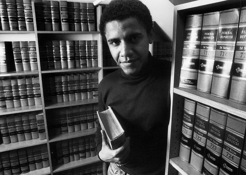 barack-obama-65-eves-10-teny | Marie Claire Barack Obama, 1990; fekete-fehér portré könyvtárban, könyvekkel a kezében