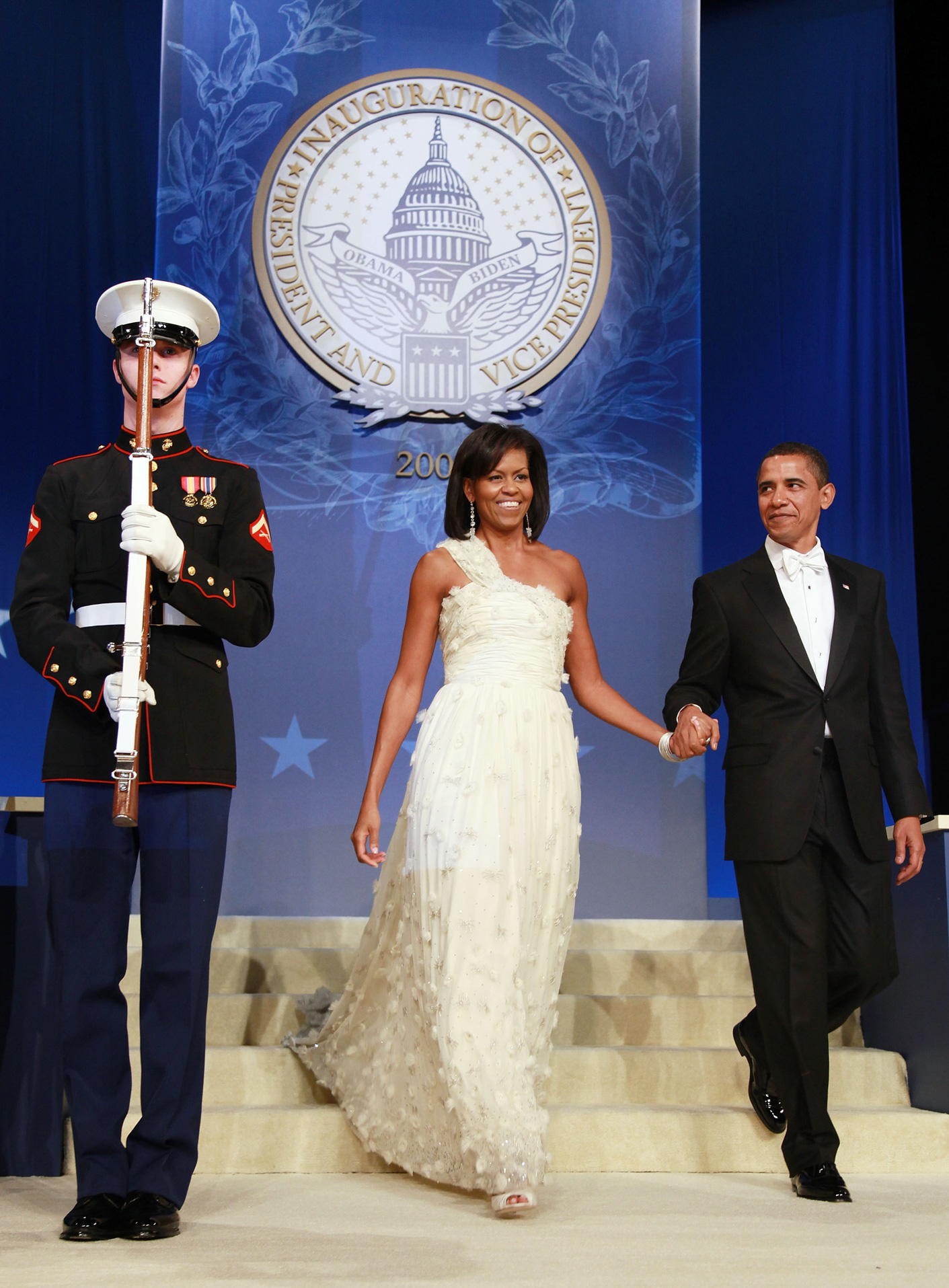 michelle-obama-legjobb-ruhaja | Marie Claire Michelle Obama fehér ruhában fogja Barack Obama kezét a beiktatási bálon