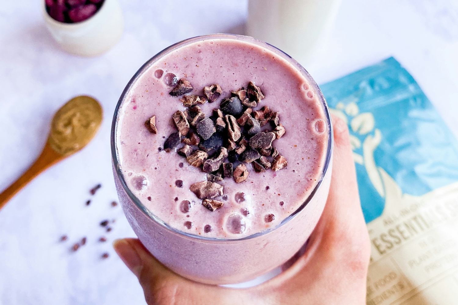 3. Fehérjedús reggeli turmix por nélkül | Marie Claire Piros bogyós gyümölcsökből készült lila reggeli smoothie-t fog női kéz