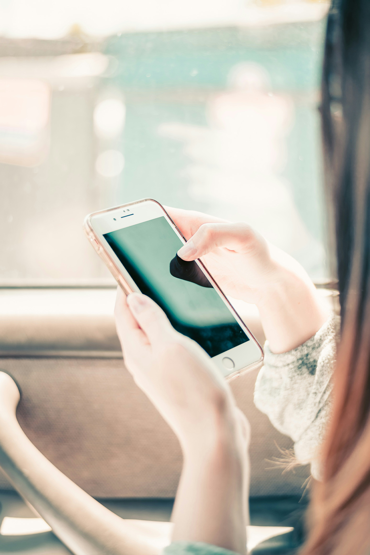 Egy nő mobiltelefont tart a kezében a kocsiban