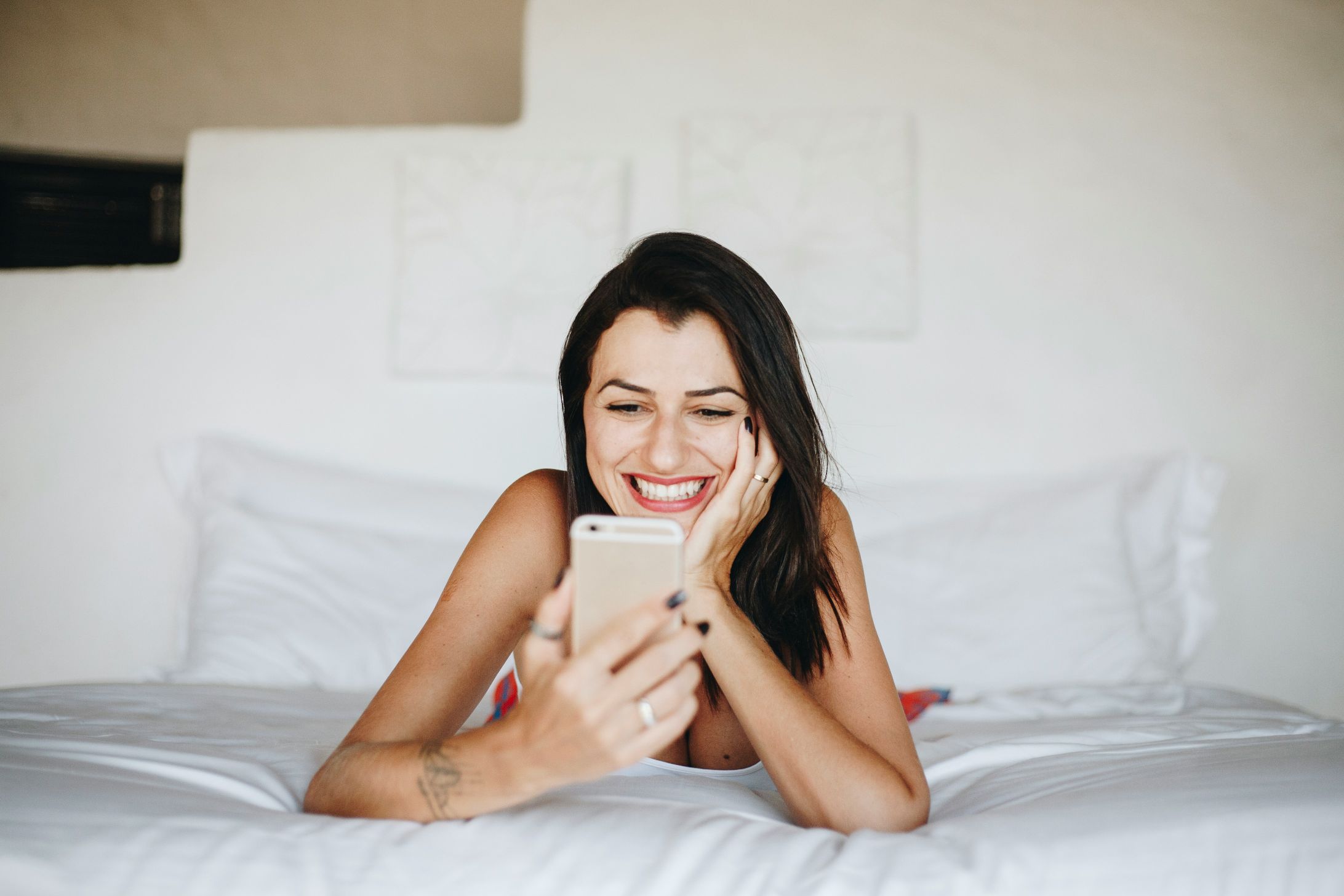 Fiatal nő a telefonjára mosolyog