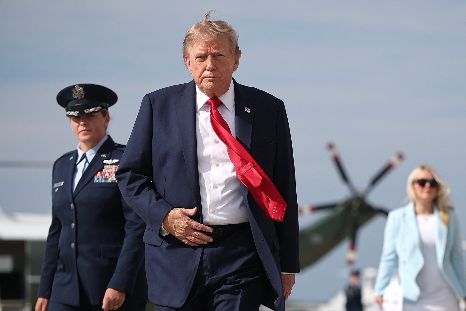 Donald Trump 2026. augusztus 21-én repülőtéren, mögötte egy pilóta áll