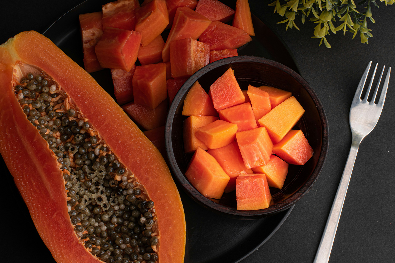 Egy fél papaya az asztalon, mellette felkockázva is egy kis tálban