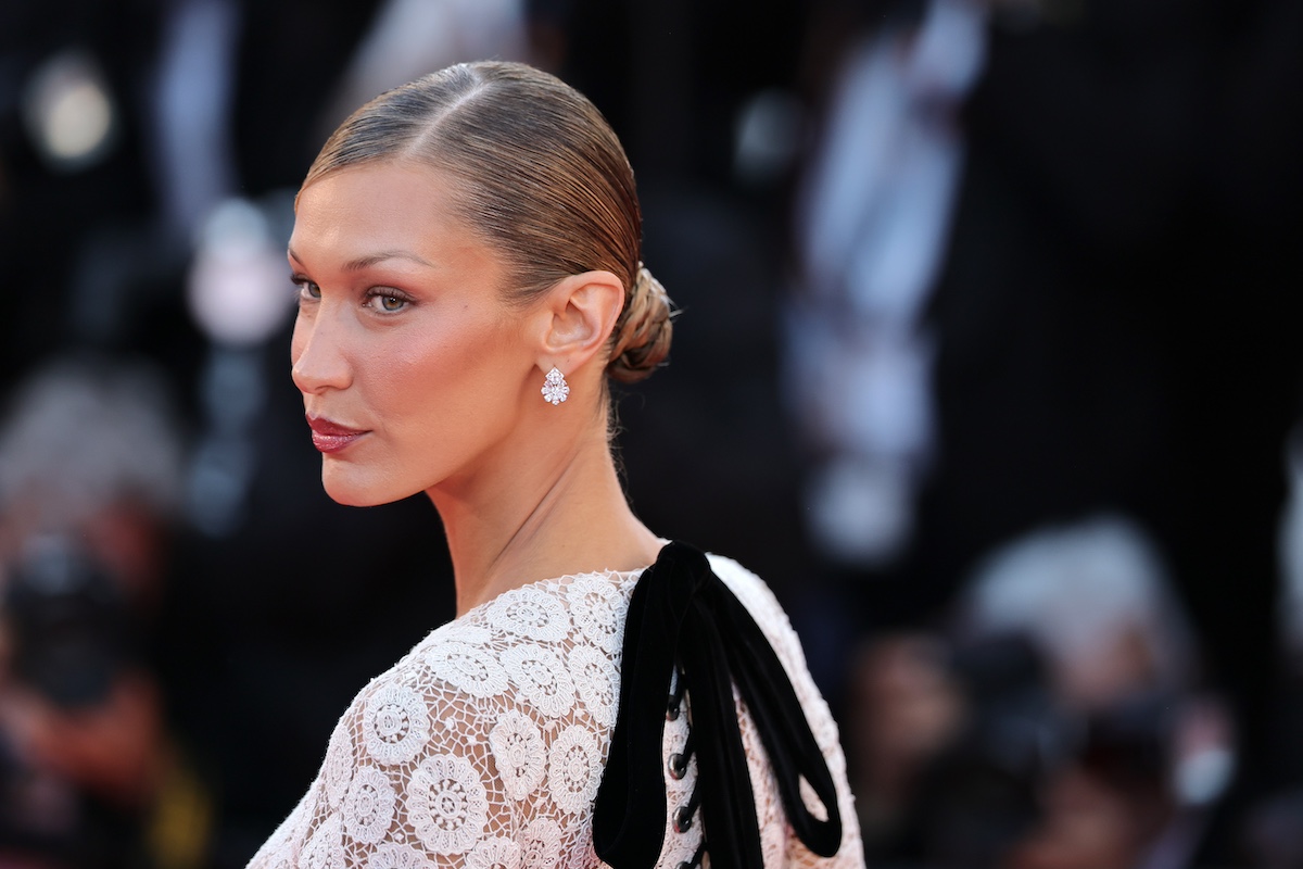 Bella Hadid csipkeruhában, masnival, félig háttal, szőke konttyal