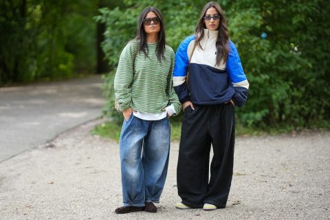 barna hajú modellek farmerben, bokrok előtt állva