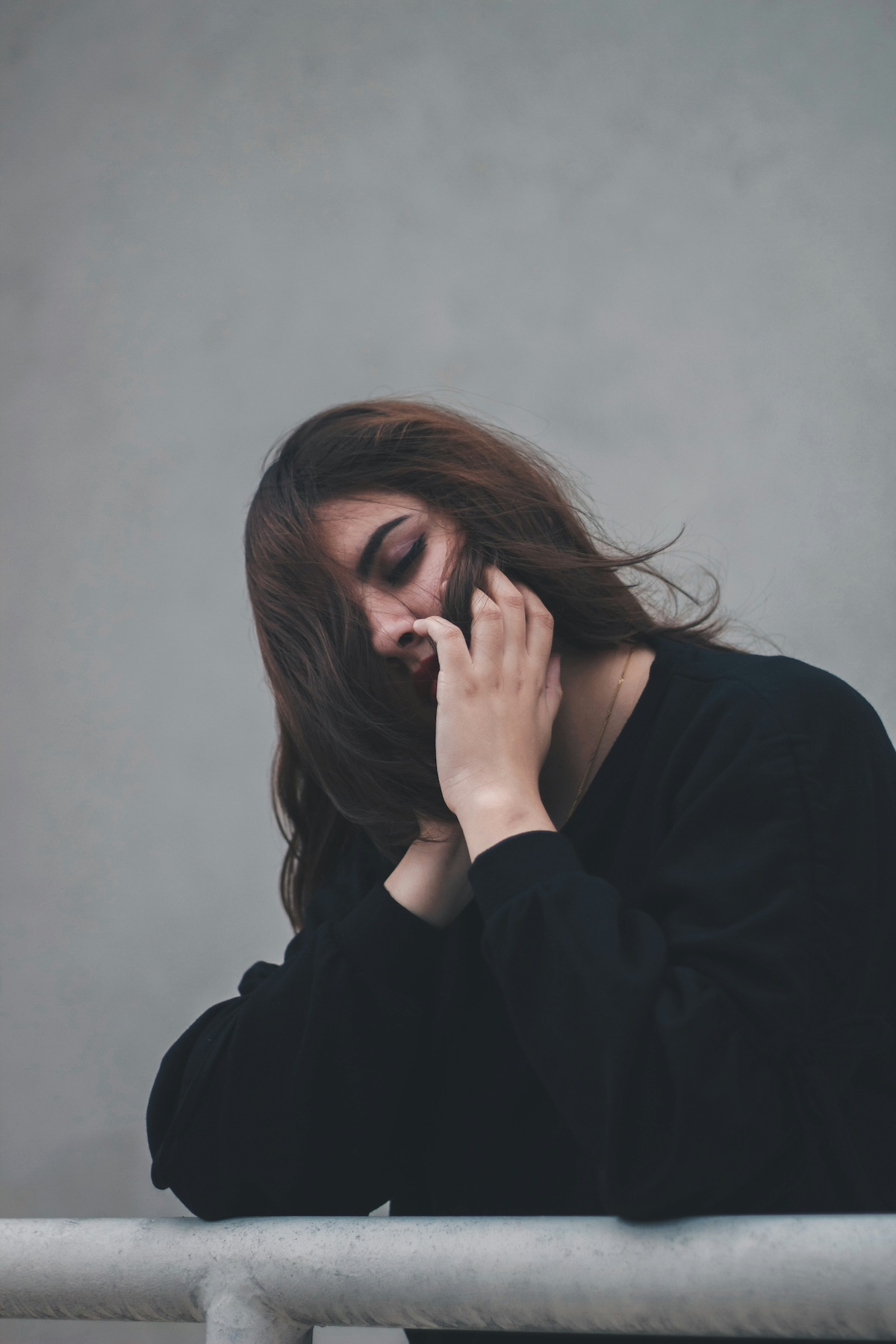 mergezo-ember-vedekezes | Marie Claire szomorú barna hajú, fekete pulóveres nő az arca előtt a haját babrálja