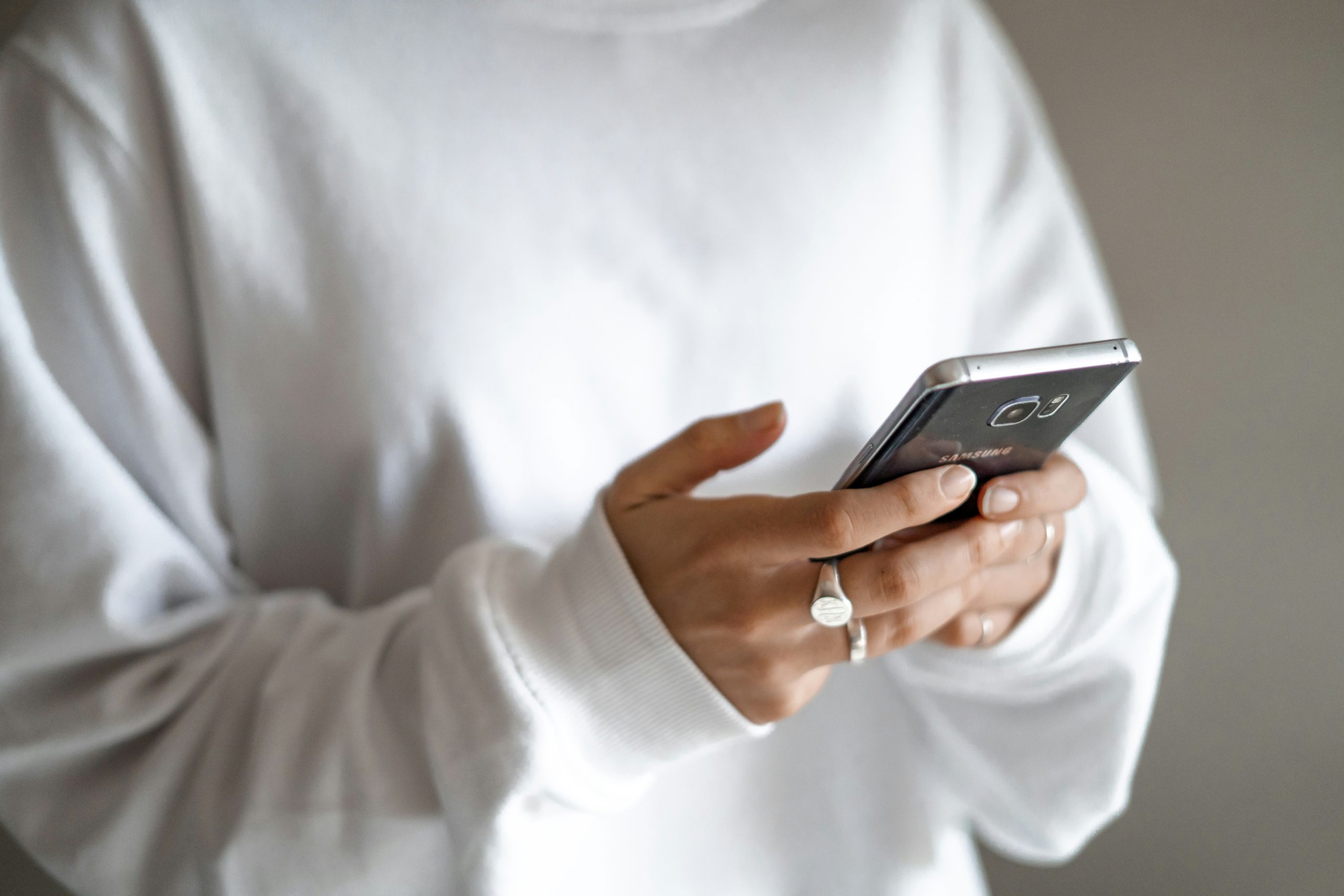 Lány fehér felsőben gyűrűkkel mobiltelefonozik
