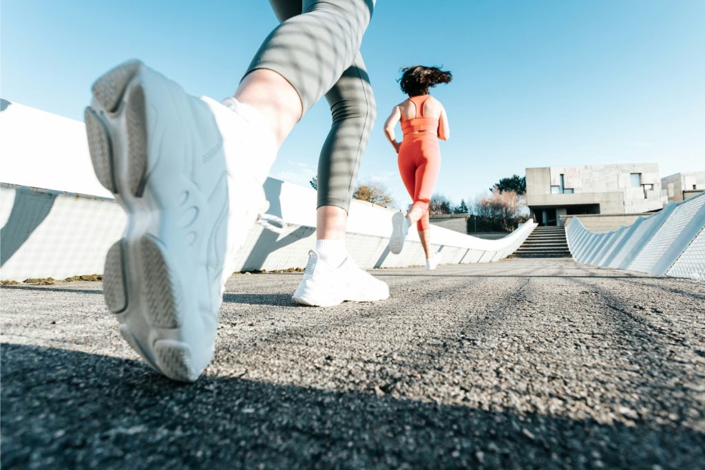 lassu-futas-hatasa | Marie Claire Nők aszfalton futnak, fehér edzőcipőn a fókusz alulról fotózva