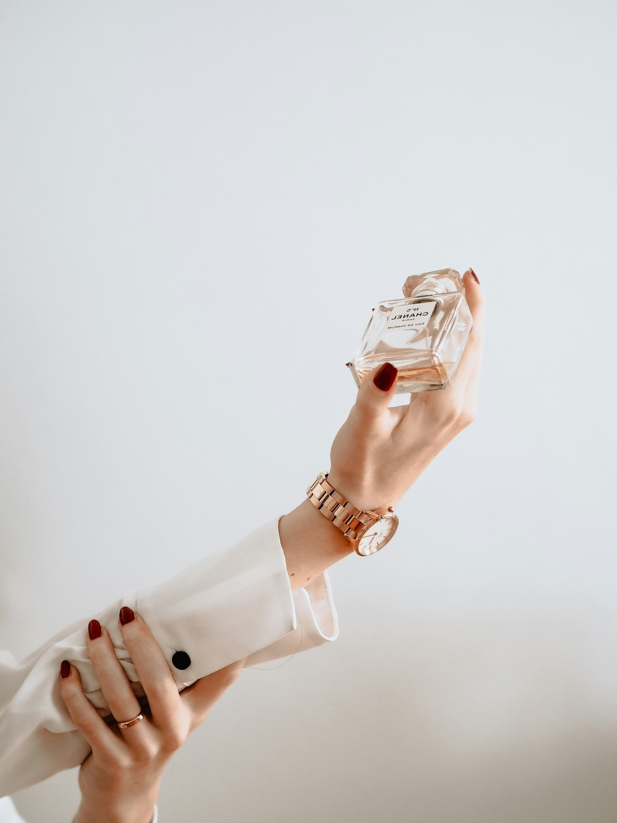parfum-megromlik | Marie Claire parfümöt tartó női kéz fehér háttér előtt
