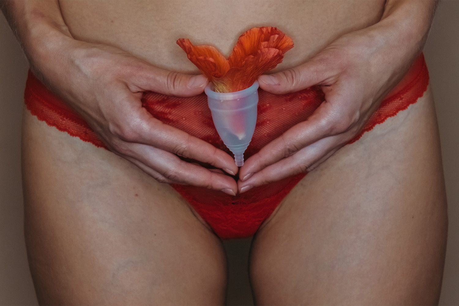 Egy nő menstruációs kelyhet tart a kezében, amiben virág van