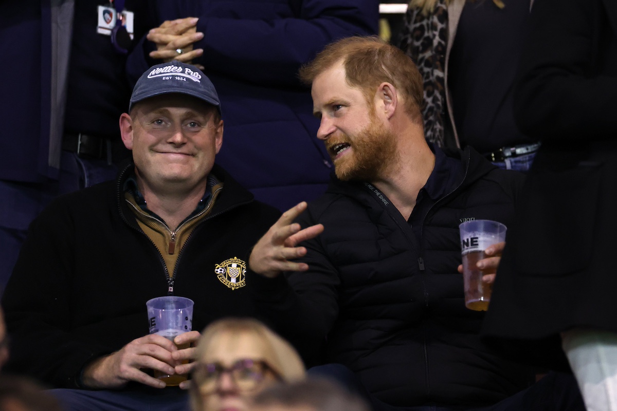 Harry herceg sörrel a kezében egy baseball sapkás férfival beszélget