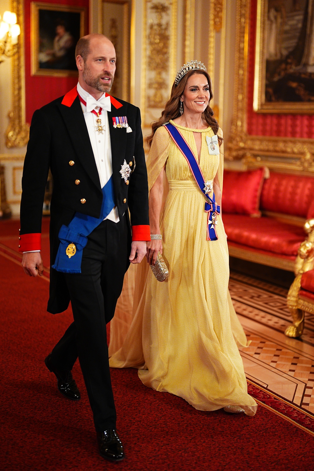 katalin-hercegne-diana-lovers-knot-tiara-oman | Marie Claire Vilmos herceg vörös szőnyegen vonul és mellette Katalin hercegné sárga ruhában, tiarával