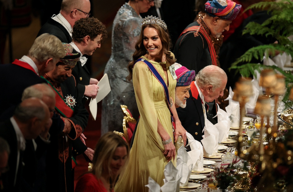 katalin-hercegne-diana-lovers-knot-tiara-oman | Marie Claire Katalin hercegné sárga ruhában, tiarával banketten hátrafele néz és mosolyog