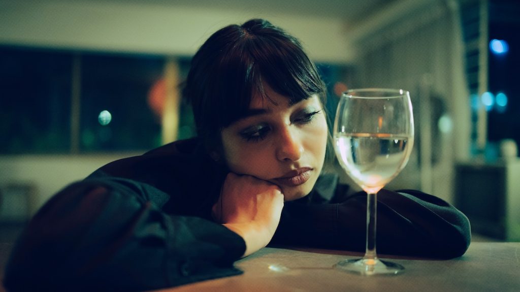 alkohol-hatasa-emberi-szervezetre | Marie Claire Nő bánatosan néz egy boros poharat a fejét támasztva