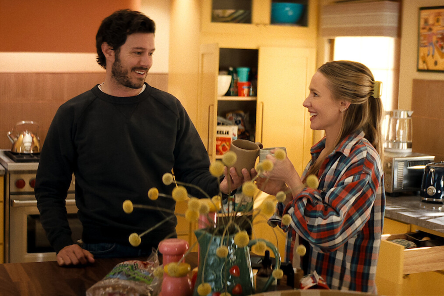 Bármit csak ezt ne 3. évad jelenetfotó konyhában, Adam Brody és Kristen Bell bögrékkel koccintanak