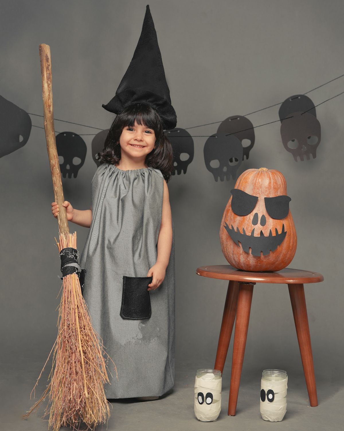 halloweeni tök mellett boszorkánynak öltözött kislány