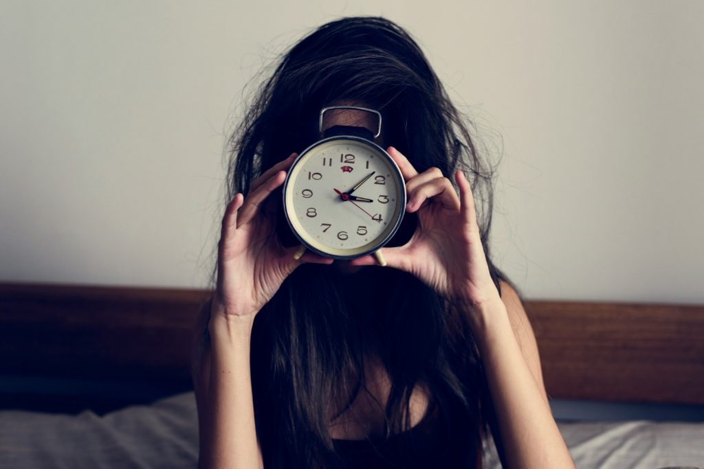 cirkadian-depresszio-belso-ora | Marie Claire Nő vekkerórát tart az arca elé ágyon ülve
