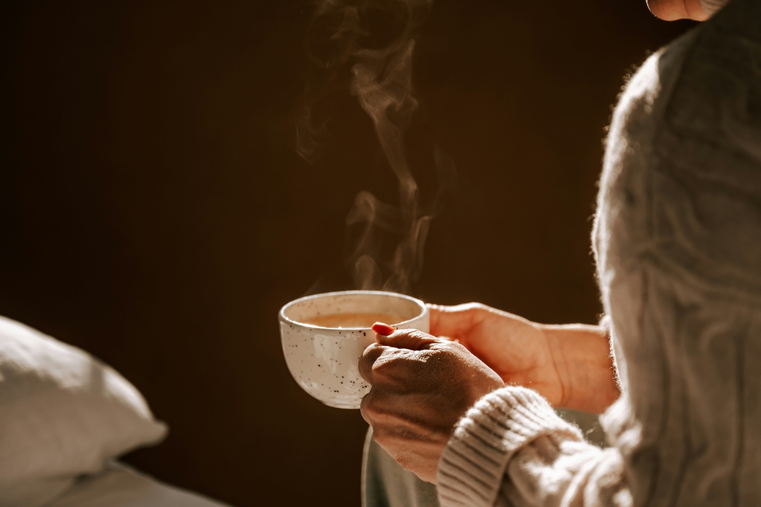 Nő gőzölgő gyömbérteát fog a kezében esti fényben