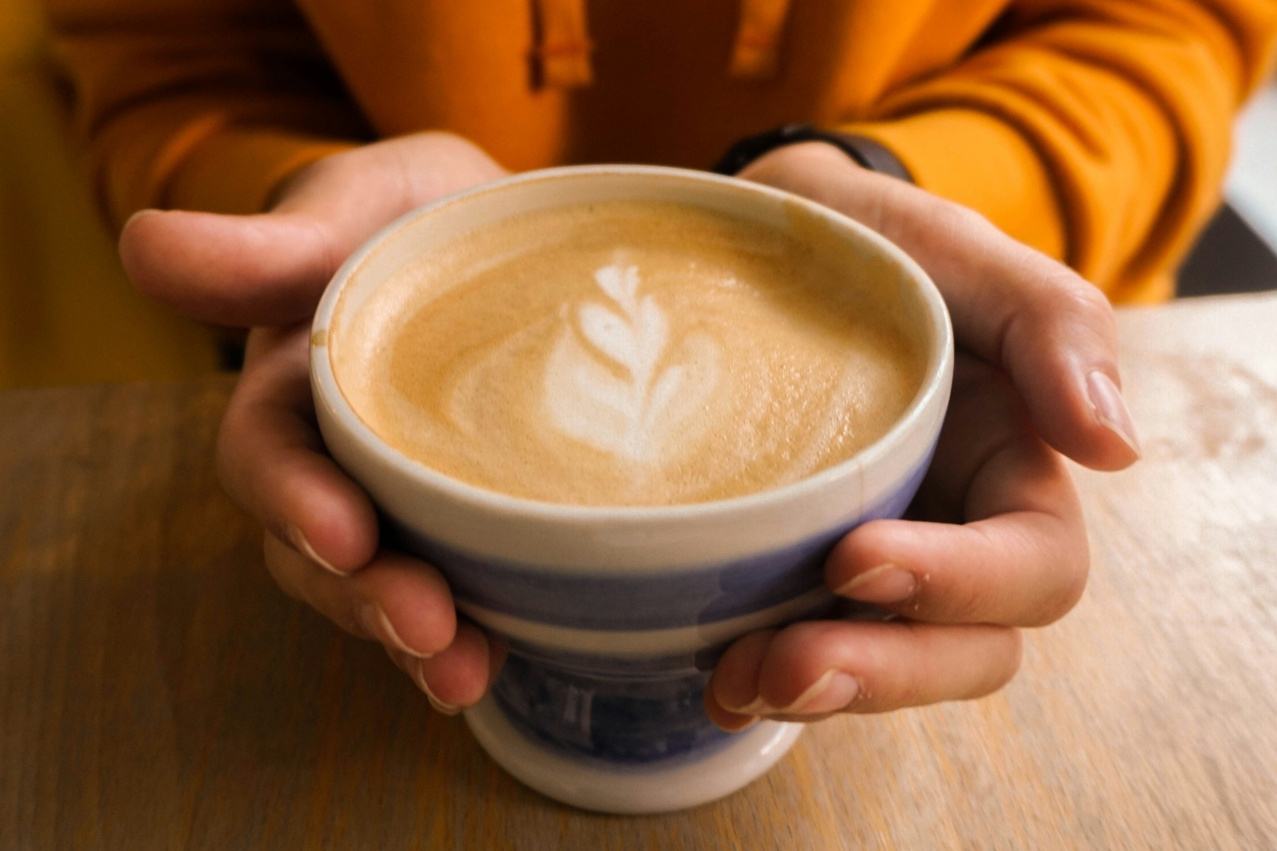 Fiatal női kéz flat white kávét tart
