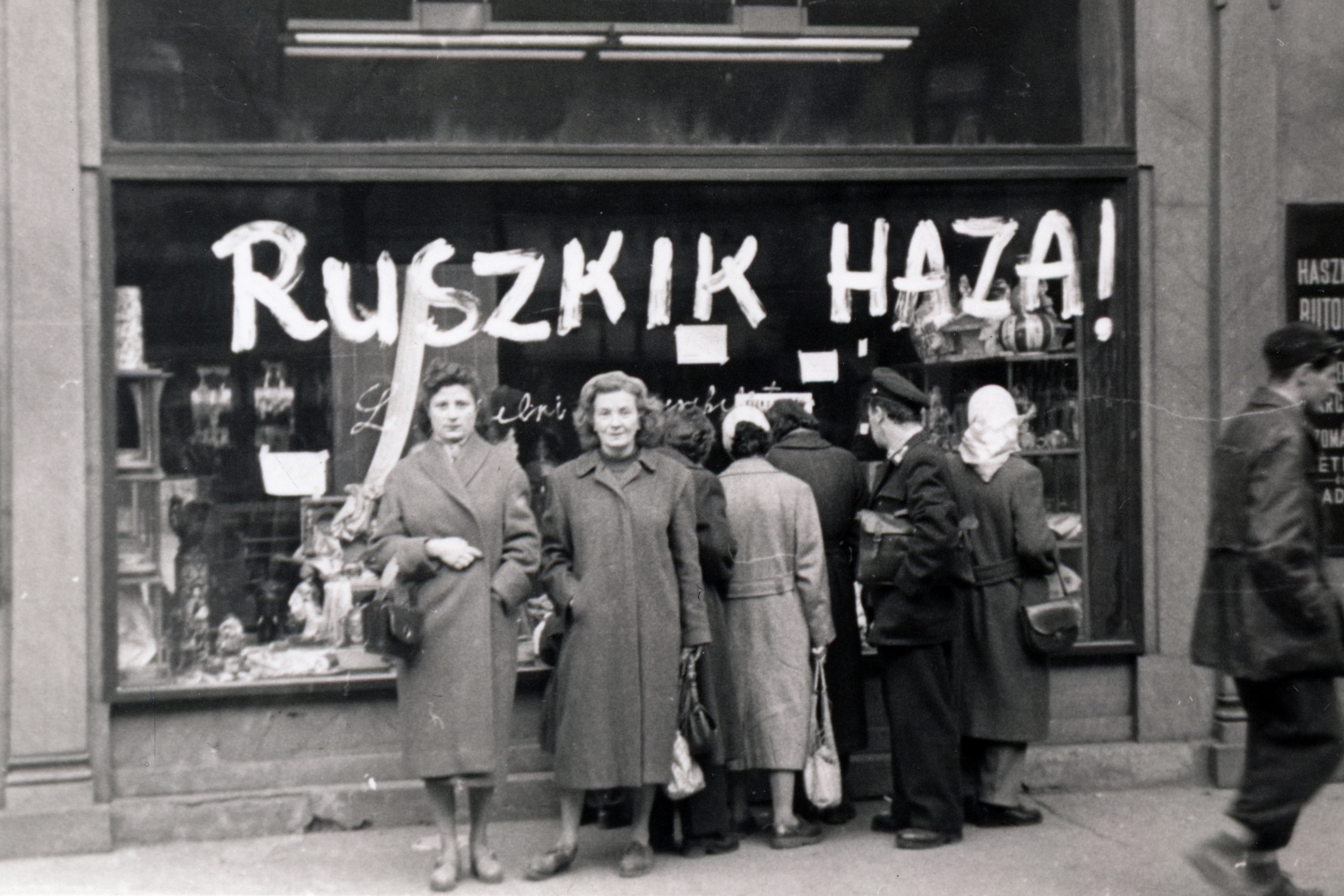 Ruszkik haza! felirat kirakat üvegén 1956-ban, előtte nők állnak a kamerába nézve