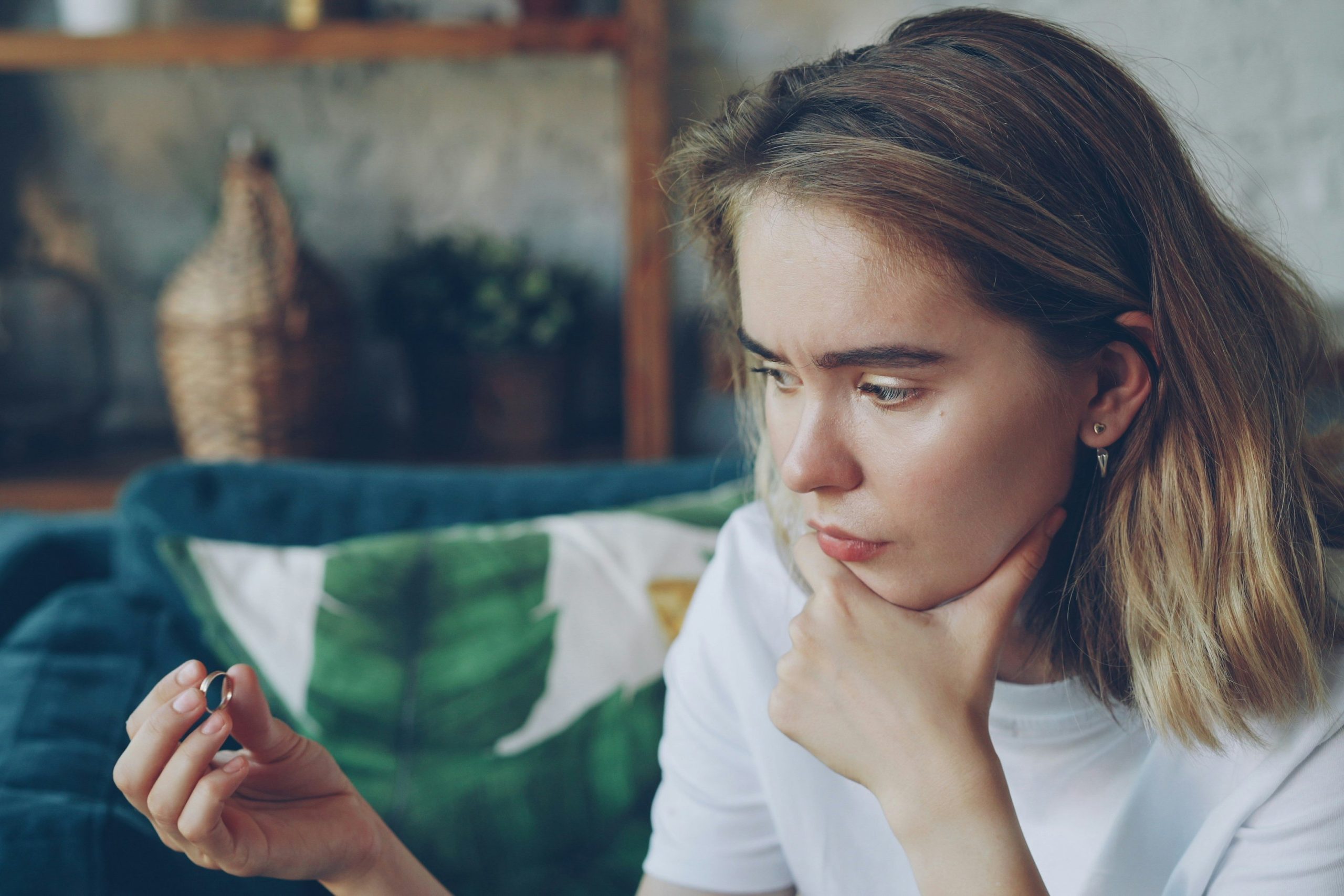 oldalra néző, boldogtalan nő, a háttérben zöld levélmintás párna